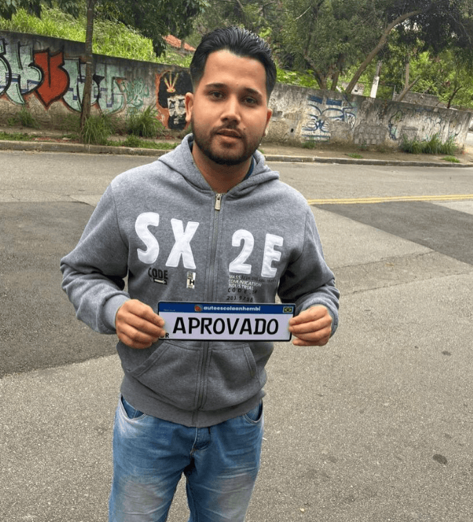 Aluno aprovado da Anhembi Auto Escola segurando a placa de aprovação