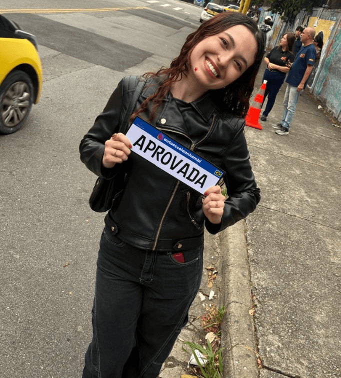 Aluno aprovado da Anhembi Auto Escola segurando a placa de aprovação