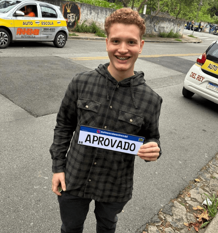 Aluno aprovado da Anhembi Auto Escola segurando a placa de aprovação