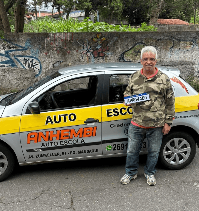 Aluno aprovado da Anhembi Auto Escola segurando a placa de aprovação