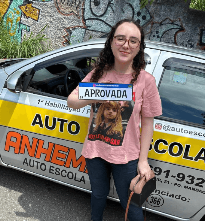 Aluno aprovado da Anhembi Auto Escola segurando a placa de aprovação